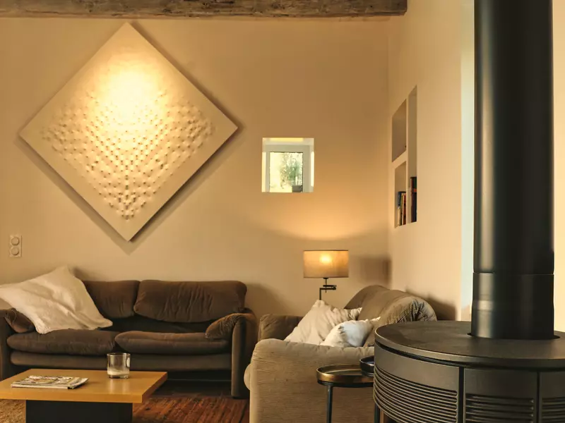 le salon du gite de la cubane en tarn et garonne, un tableau contemporain sur un mur, un poêle à bois sur le devant droit, une table basse, des canapés, une ambiance chaleureuse