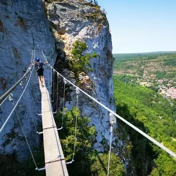 vue de la Via Ferrata du roc d'Anglars à Saint-antonin noble val, tarn et garonne au niveau des gorges de l'aveyron ; en premier plan une passerelle surplombant le vide, dans le fond la falaise vers laquelle se dirige un utilisateur
