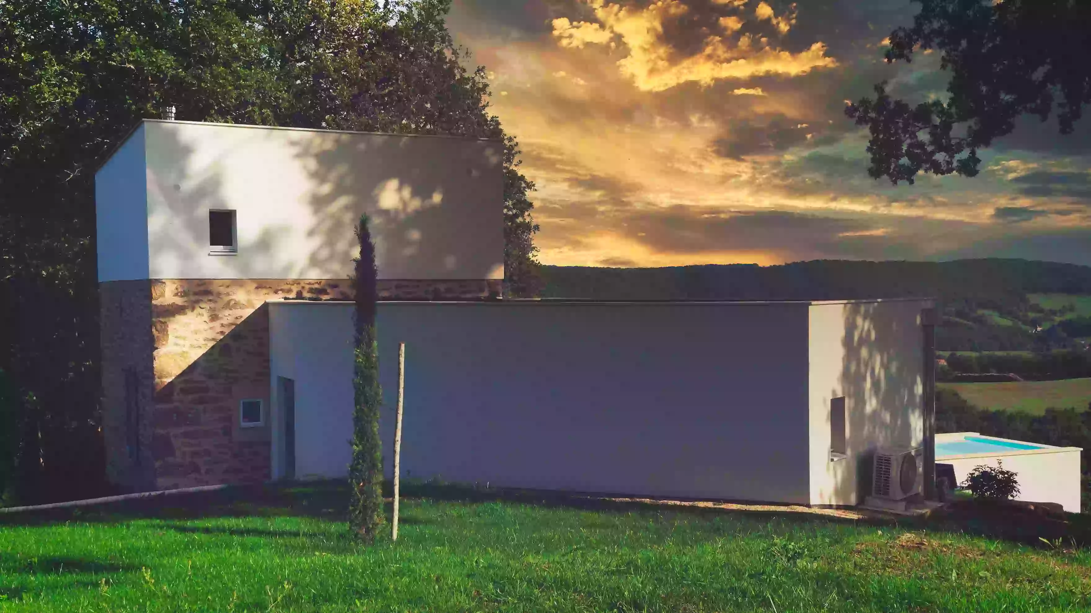Le gîte de la cubane au soleil couchant ; vue de la façade nord avec le bloc central, l'aile ouest, la pelouse sur le devant