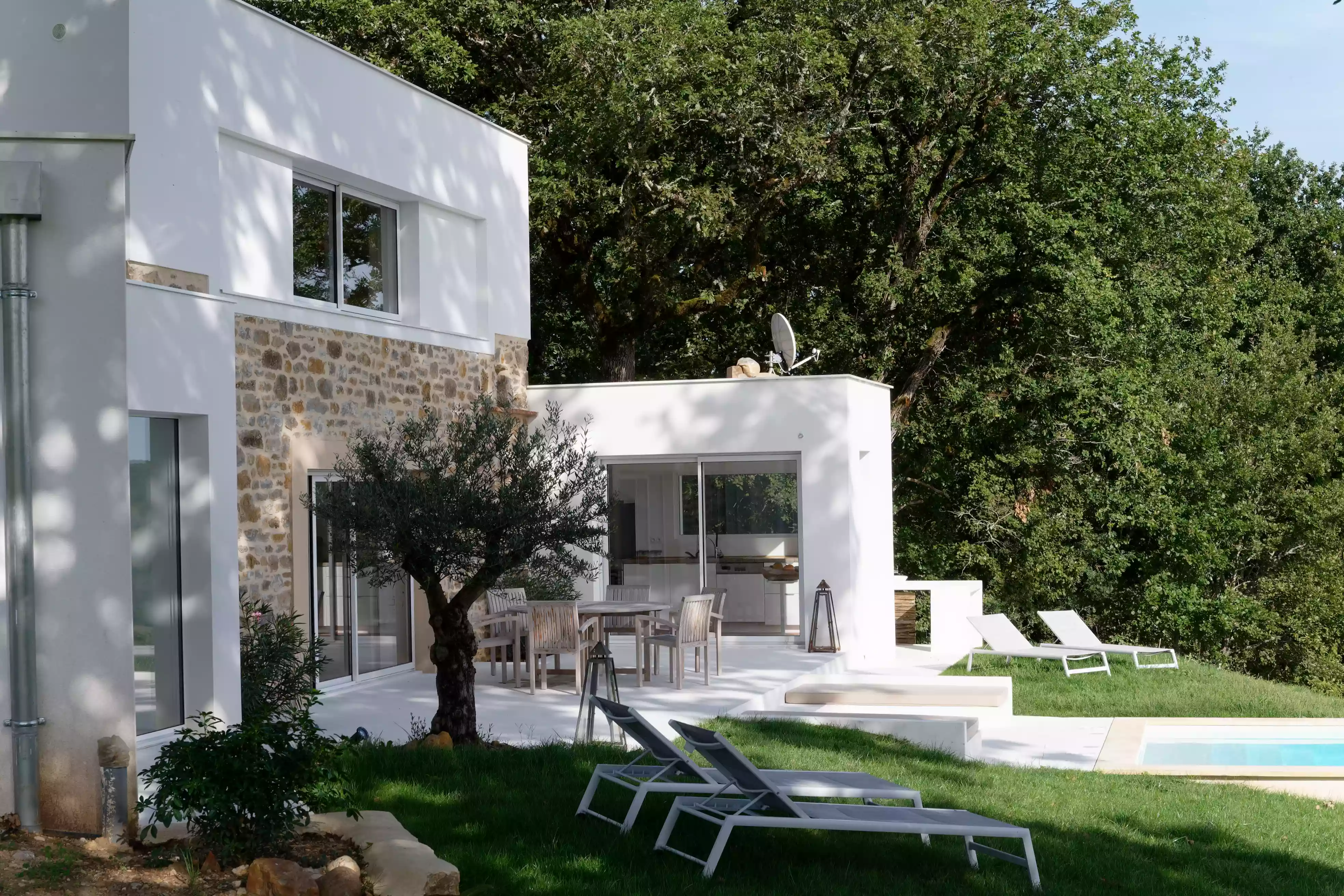 le gîte de la cubane, façade sud avec le bâtiment central sur deux niveaux, salon au rez-de-chaussée et chambre à l'étage, et à l'est l'aile de la cuisine ; vue sur la piscine et l'olivier