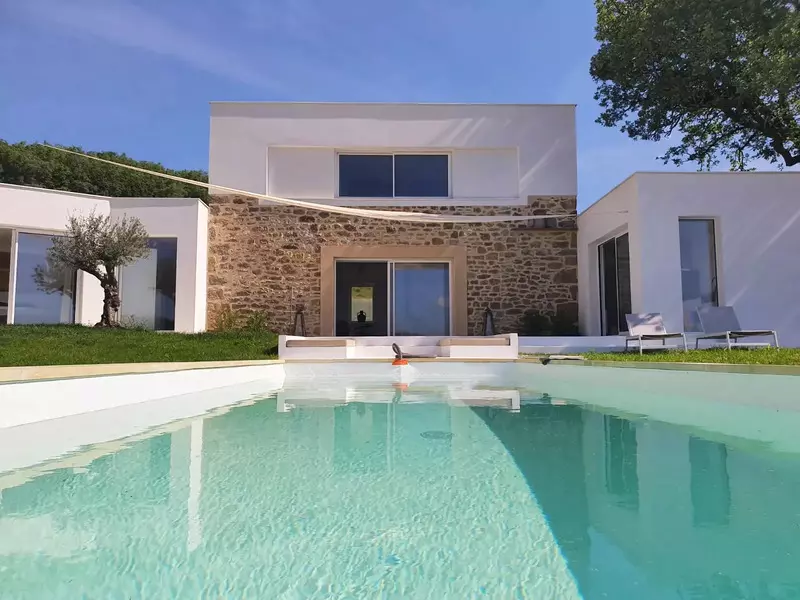 gîte à proximité de Saint-Antonin : la façade contemporaine avec le bloc central et les deux ailes ; en premier plan, la piscine, un olivier en décoration