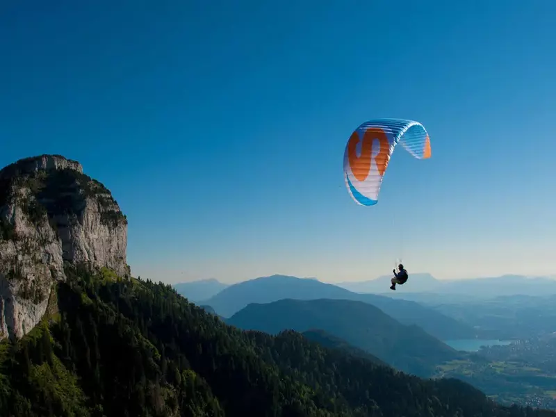 parapentiste dans un ciel bleu survolant un paysage de collines à proximité des gorges de l'aveyron