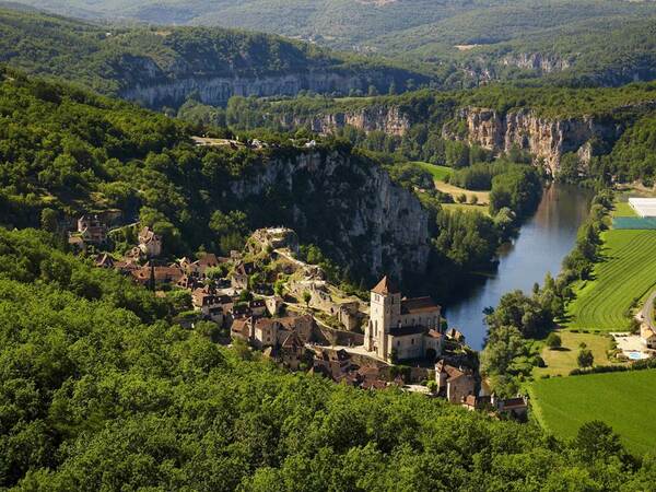 le village de saint-cirq lapopie en occitanie qui surplombe la vallée du lot ; au fond les gorges de la vallée, devant le village ramassé avec son église, ses maisons