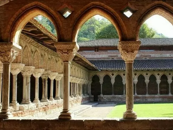 le cloitre de l'abbaye de moissac dans le tarn et garonne, région occitanie ; on aperçoit trois chapiteaux et arcades en ogives au premier plan et sur le côté gauche de la photo et dans le fond les rangées de chapiteaux et arcades.