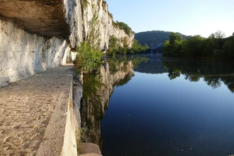 Le chemin de halage sur les berges du lot au niveau de saint-cirq lapopie ; le chemin est creusé à flanc de falaise et pavé ; il passe sous la roche qui est en surplomb. Sur la droite de la photo, la riviére